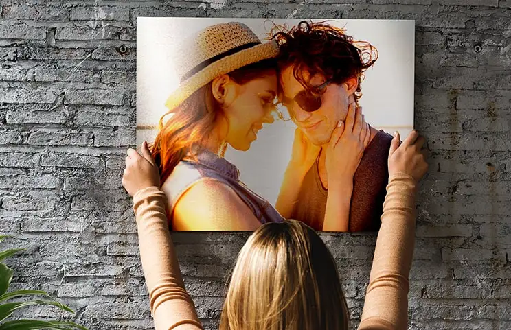 Woman placing metal print of girlfriend and boyfriend on wall