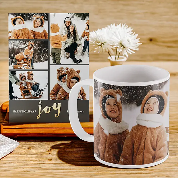 A photo mug with two children in winter coats, beside a holiday card