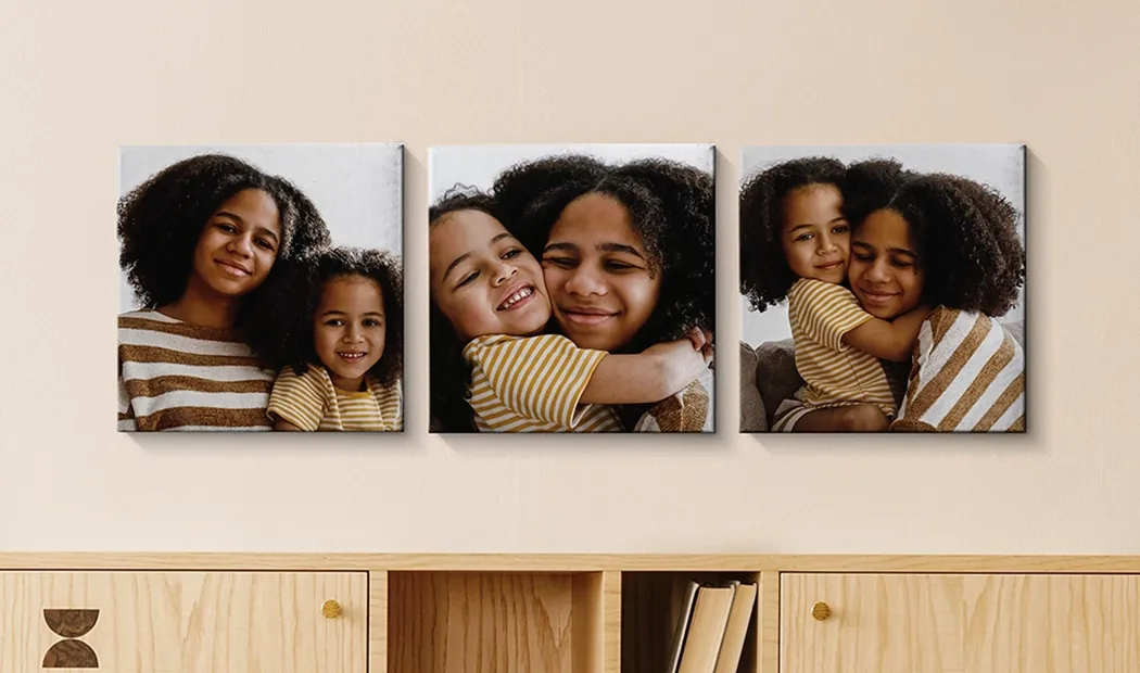 Photo Canvas Display Panels by Printerpix|Canvas Panels|Man and woman putting up a photo canvas with a holiday photo on|Woman putting up three black and white family photo canvases|Mom and four young kids sitting on sofa in front of four photo canvases|Couple in front of blue wall with nine square photo canvases on|||||