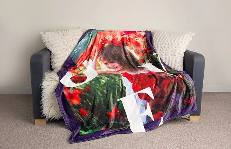 A personalised Printerpix mink blanket with a child on it, draped over a sofa.. The word “love” is visible.
