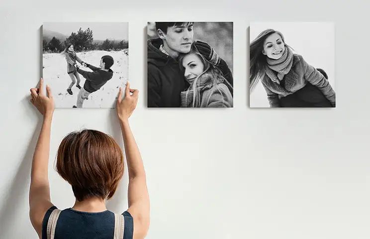 Woman putting up three black and white family photo canvases