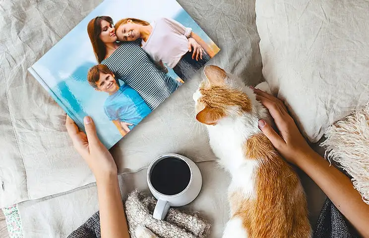 Pet and woman looking at personalised family photo book with custom design