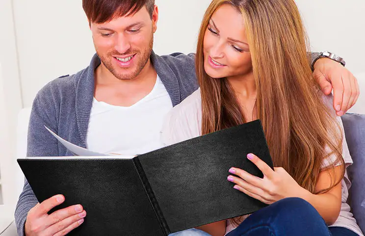 Couple look at leather cover custom photo book made by Printerpix